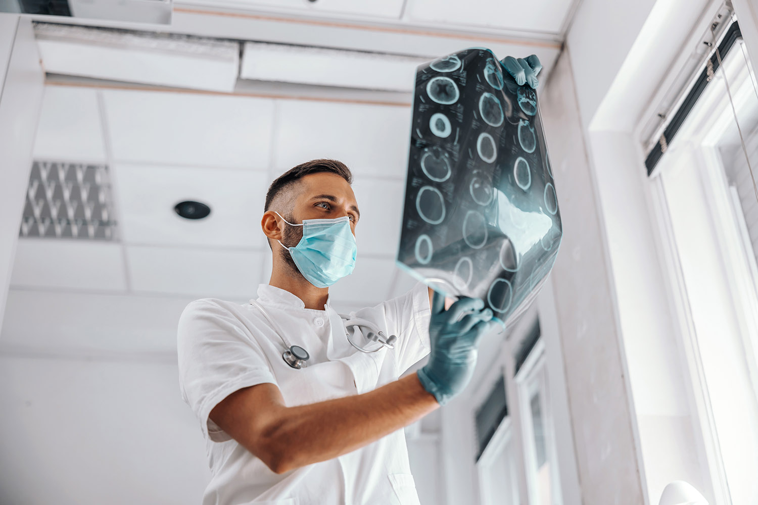 Bottom view of dedicated doctor holding x-ray of the patient’s b AdobeStock 371745997