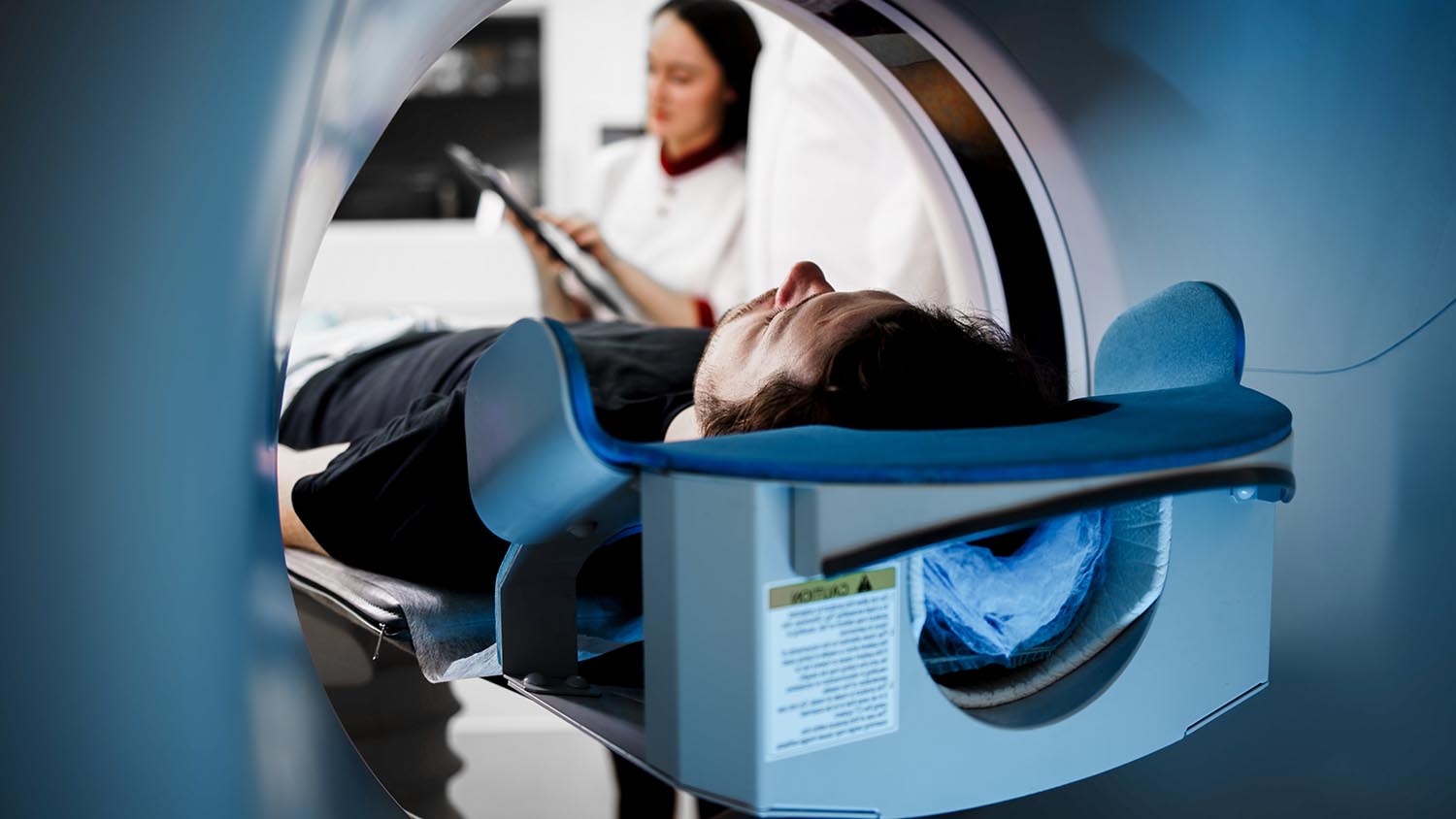 Patient undergoing CT scan in modern medical facility, with tech AdobeStock 1772806267
