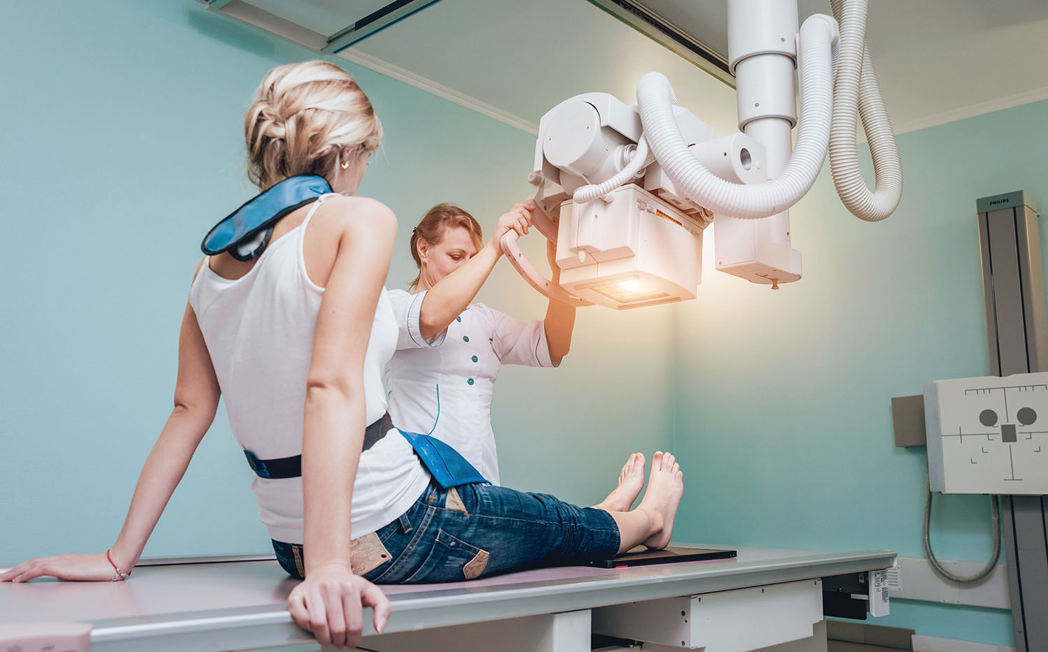 Radiologist and patient in a x-ray room. Classic ceiling-mounted x-ray system. AdobeStock 196892769