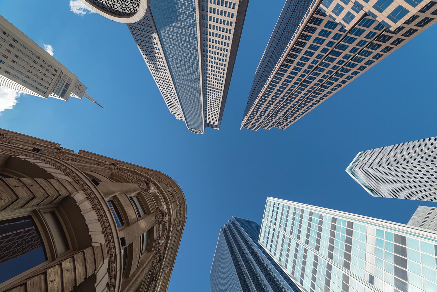 Upward view of skyscrapers against blue sky in the business dist AdobeStock 235248026